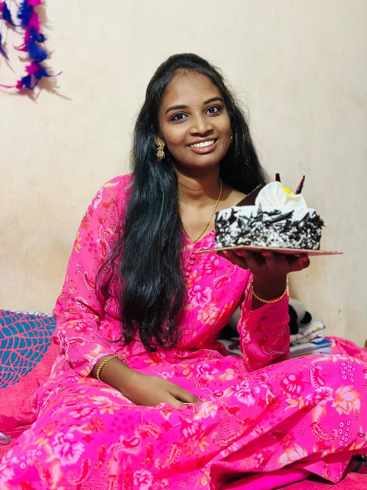Kavya smiling in a pink dress while holding her birthday cake